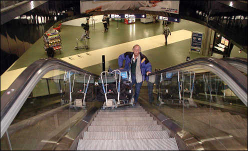 Kenny coming up escalator with a huge cart of luggage